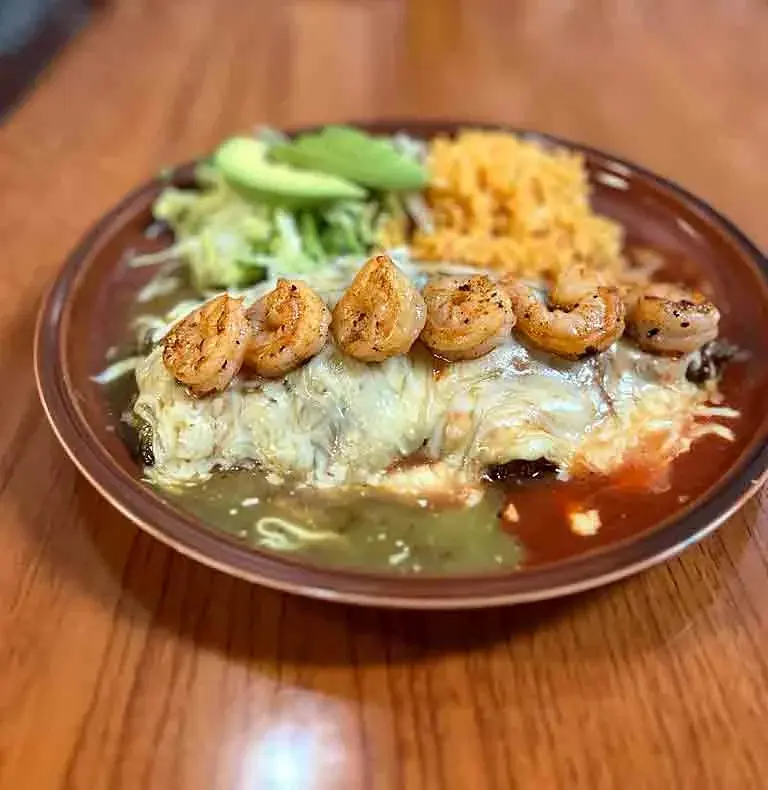 Enchiladas topped with grilled shrimp, rice and avocado