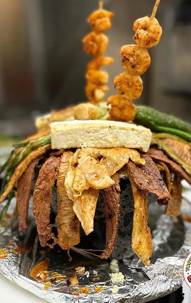 A molcajete with grilled meats and shrimp skewers