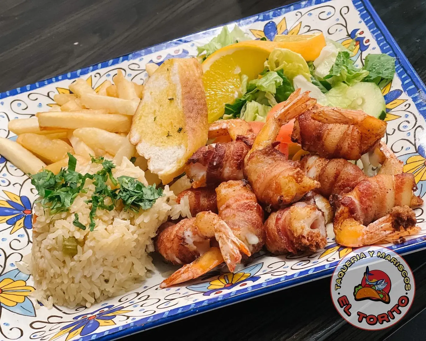 Bacon-wrapped shrimp with rice, fries and salad