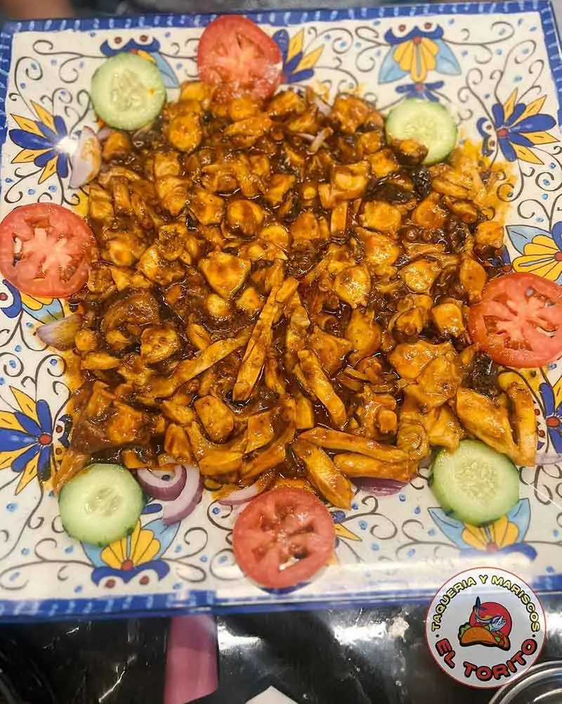 Pulpo en salsa roja on a talavera platter